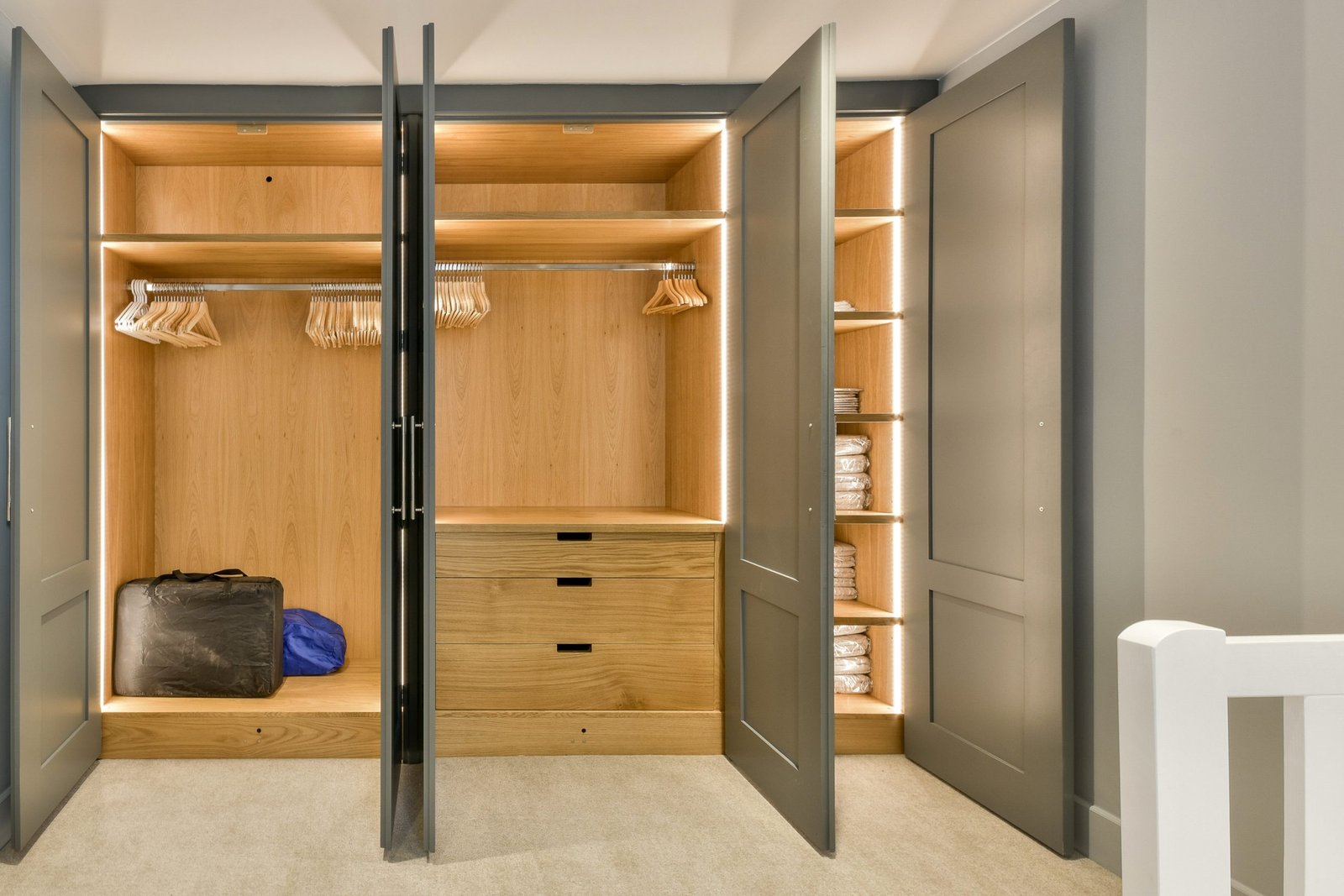 a walk - in closet with clothes hanging on the wall and an open door that leads to a bathroom area